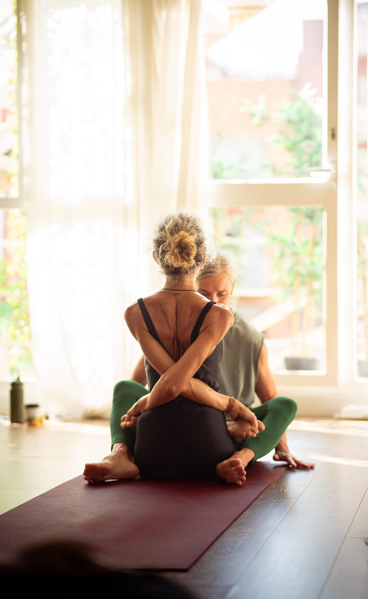 Lotta seated in a bound posture in warm window light